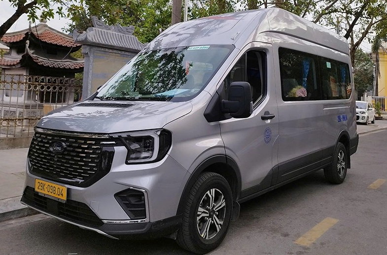 Silver Ford Transit minibus viewed from the front and side on a street