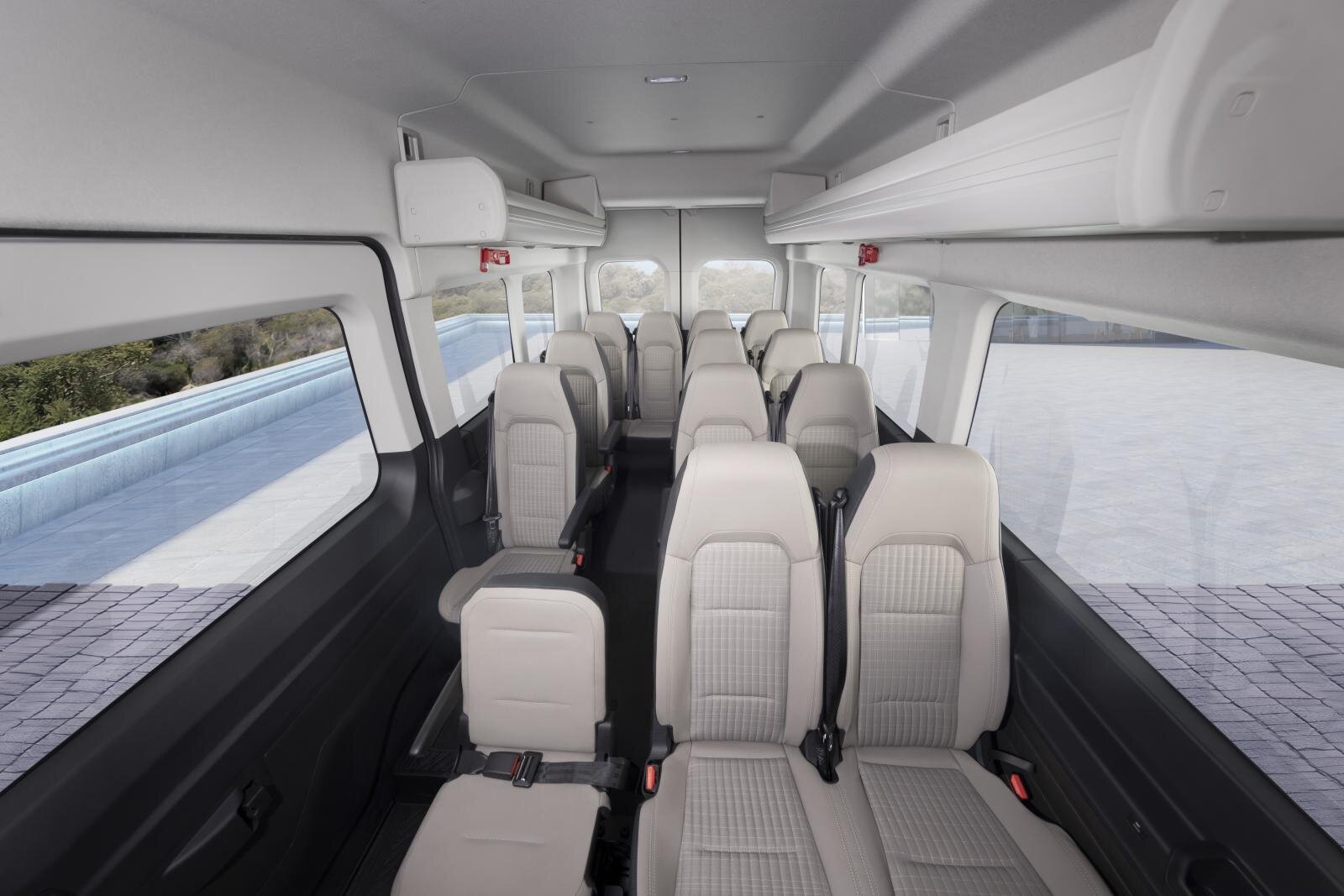 Minibus cabin with rows of light-coloured seats, seat belts and overhead shelves