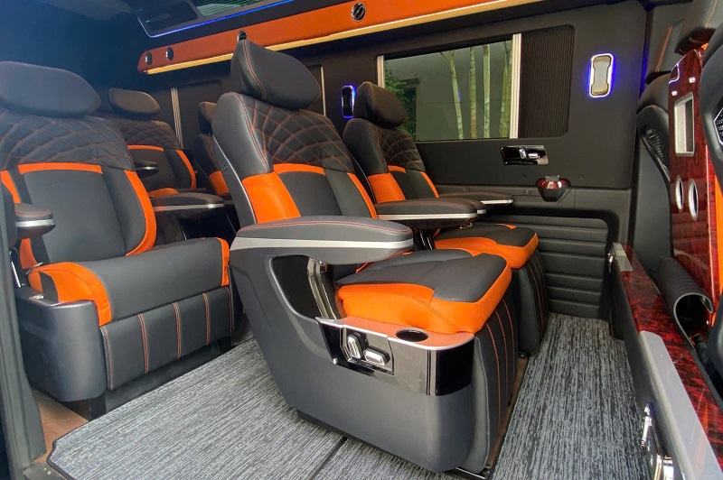 A different limousine cabin with orange-and-grey individual seats, armrest controls and cupholders
