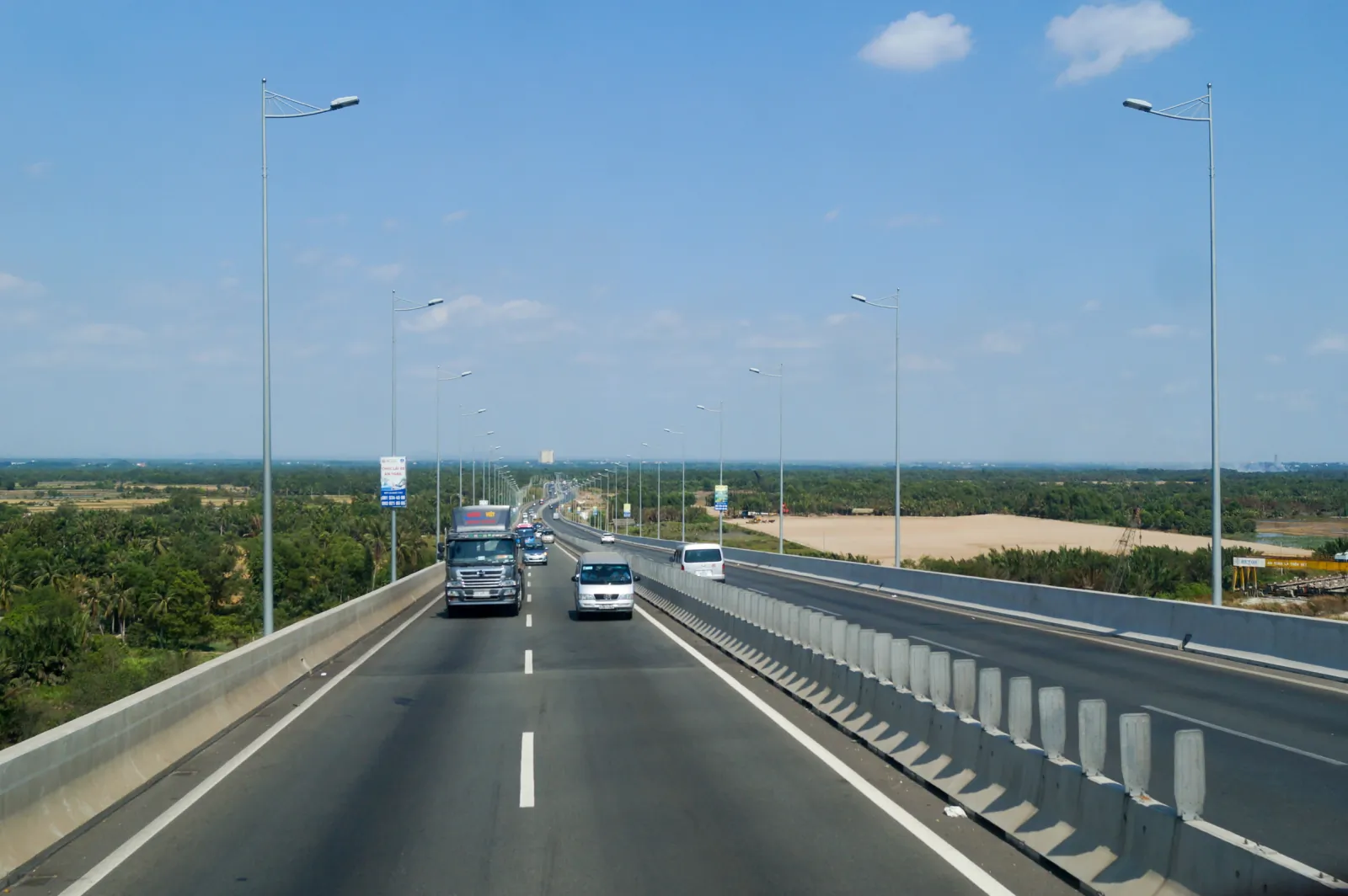 Truck and white minibus on the elevated Ho Chi Minh City–Long Thanh–Dau Giay Expressway over Long Thanh Bridge, Dong Nai, Vietnam