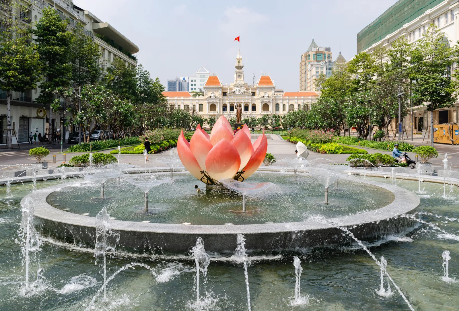 胡志明市第一郡阮惠步行街上,噴水池中立著一座粉紅色的蓮花造型雕塑,後方是橘紅屋頂的胡志明市人民委員會大樓,兩側有行道樹