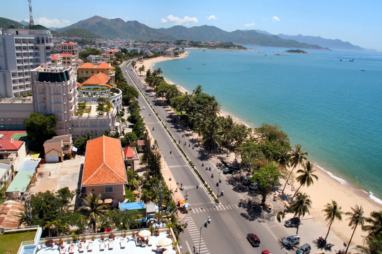 Elevated view of Tran Phu street in Nha Trang: palm trees, a sandy beach and a turquoise bay, with mountains on the horizon